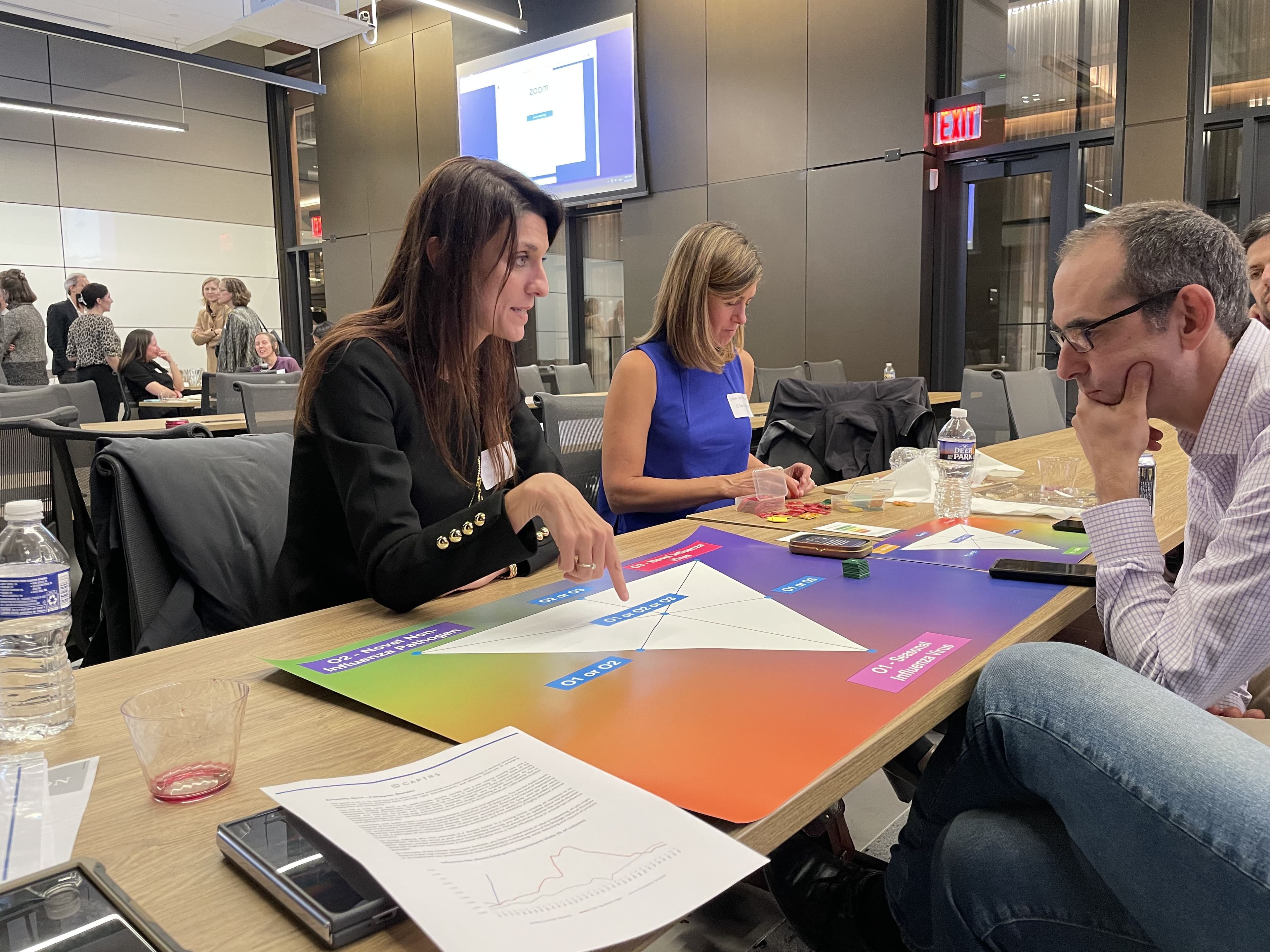 Three people around a table with a colorful board game