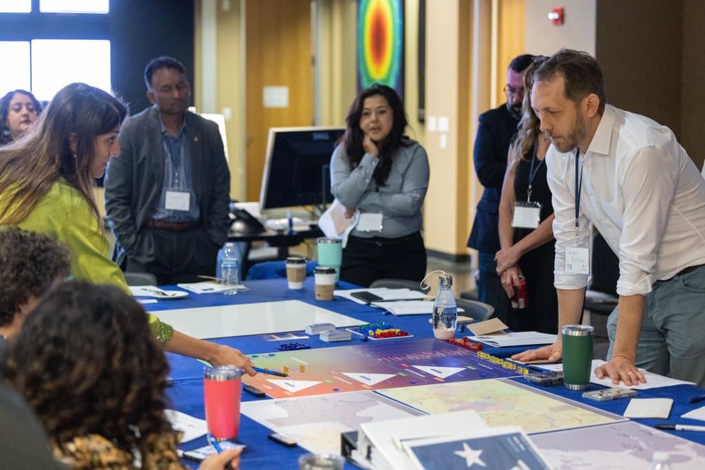 Group of people collaborating around a table with papers and maps