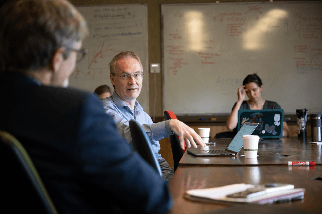 Three people in a meeting room discussing serious topics